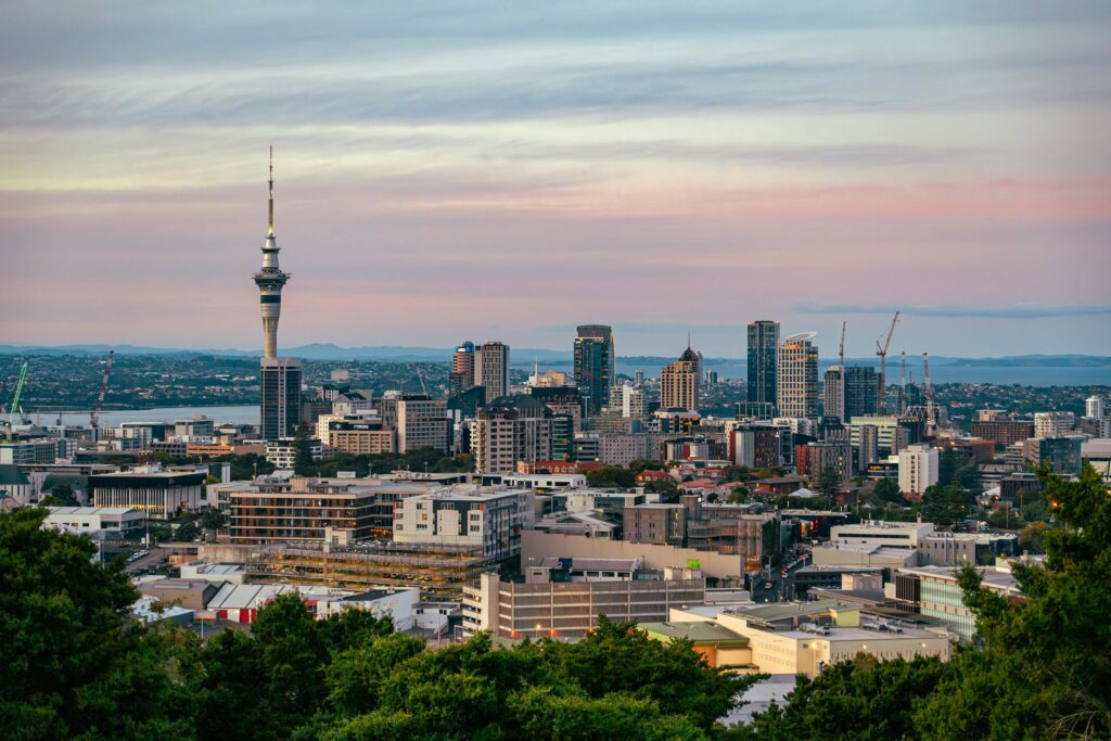 Captivating view of Auckland, New Zealand's skyline at dusk featuring the iconic Sky Tower under a colorful sky.