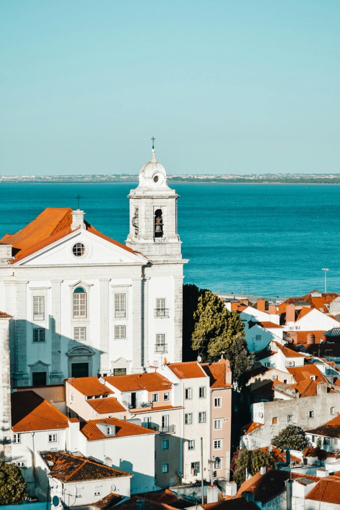 A picturesque view of Lisbon's Alfama district with traditional architecture overlooking the azure sea.