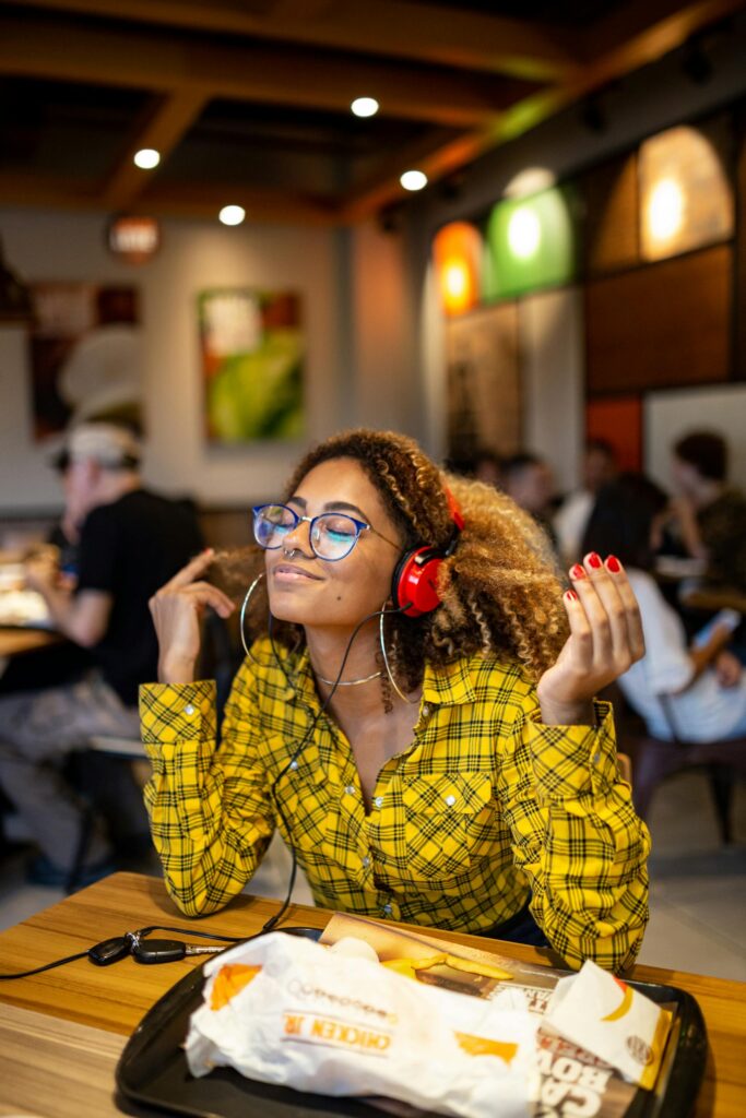 A stylish young woman with headphones enjoying music at an indoor cafe.