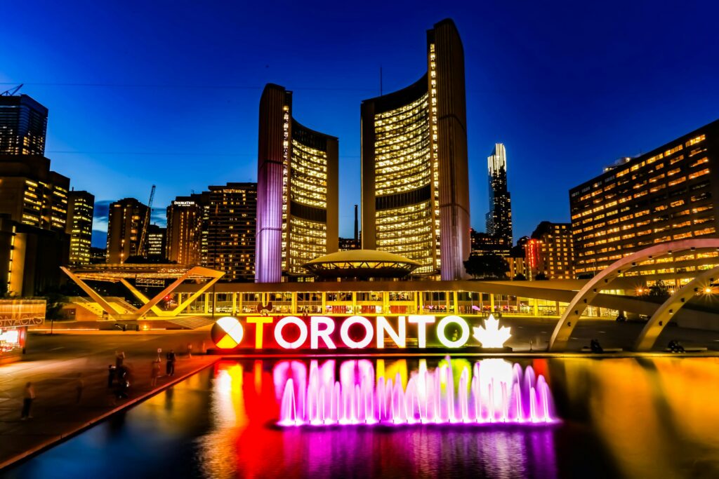 Dazzling Toronto skyline with iconic sign and fountain at dusk.